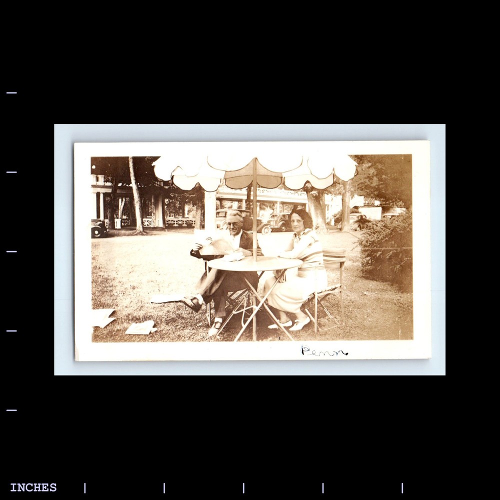 Vintage Photo of Couple at Patio Table with Umbrella and Classic Cars